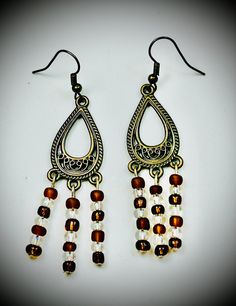 Elevate your style with these stunning Boho Chic Dangle Earrings, meticulously handcrafted to perfection. Featuring a unique vintage-inspired design, these earrings showcase a captivating teardrop motif adorned with intricate patterns. The cascading strands of high-quality Czech glass beads in rich amber and clear tones add a touch of elegance and movement to every step. Crafted with attention to detail, these earrings are perfect for any occasion, from casual outings to formal events. The light Elegant Brown Beaded Chandelier Earrings, Vintage Bronze Round Bead Earrings, Vintage Bronze Earrings With Round Beads, Elegant Brown Chandelier Earrings With Dangling Beads, Elegant Brown Earrings With Dangling Beads, Elegant Copper Earrings With Dangling Beads, Vintage Beaded Drop Earrings, Vintage Brown Round Bead Earrings, Handmade Bronze Teardrop Earrings