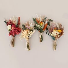 three bouquets of flowers are lined up against a white wall