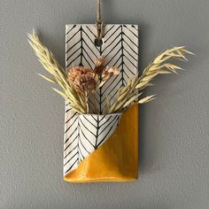 a vase with flowers in it hanging on a wall