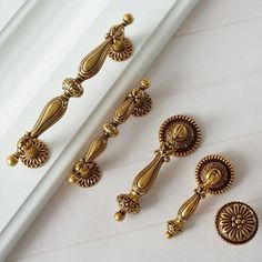 three golden door handles and two knobs on a white tablecloth with gold trimming