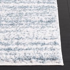 a white and blue rug on top of a wooden floor