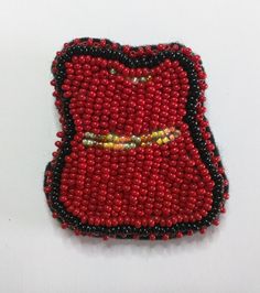 a red and black beaded brooch sitting on top of a white table