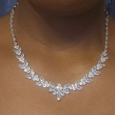 a woman wearing a necklace with leaves on it and diamonds in the middle of her neck