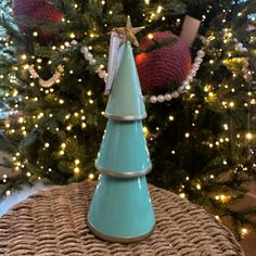 a small blue cone shaped christmas tree on top of a wicker basket in front of a decorated christmas tree