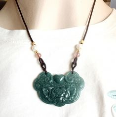 Natural Jadeite Pendant Carved Flower Longevity lock 花开富贵 长命锁 with Chain Adjustable Necklace Length 16-28 inches Pendant length about 47mm, width about 35mm.  Necklace length 16-28 Inches Adjustable. Necklace come with colorful silk jewelry bags in random color. The price is for one piece. The photo in the back was taken in the sun. If you want other cord color different with picture showed please note the color when you make order. Cord color brown black green red Optional. Green Flower Pendant Jewelry With Adjustable Chain, Handmade Jade Flower Pendant Necklace, Handmade Jade Necklace With Flower Pendant, Green Adjustable Amulet Necklace, Adjustable Green Amulet Style Necklace, Adjustable Green Amulet Necklace, Silk Jewelry, Jade Pendant, Adjustable Necklace