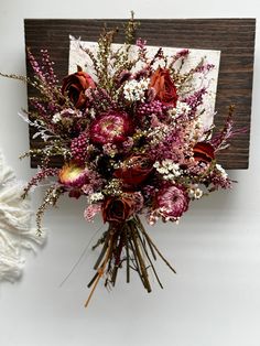 a bouquet of flowers sitting on top of a wooden frame next to a white wall