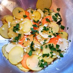 a metal bowl filled with potatoes and carrots