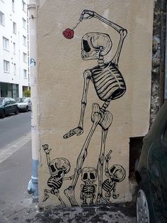 a painting on the side of a building with a skeleton holding a rose in it's hand