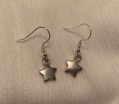 These Dainty, Glistening Silver Star Drop Earrings are the perfect accessory to complement any outfit. Each pair is handmade and produced in very small quantities, so you're guaranteed to have a unique look.                   ❤ Please note that each earring is not perfeclty identical to its counterpart - our jewelry is made entirely by hand,                        so slight variation does occur.    ------------------------------------------------------------------------------------------------------------------------------------------------------------------------- Caring for your jewelry: ❤ Please handle these earrings with care as they are delicate. Our earrings are made to withstand normal wear, but are vunerable to being damaged if extensive pulling/tugging occurs.  ❤ Avoid getting wet Silver Earrings With Star Charm For Everyday, Metal Earrings With Star Charm For Gift, Dainty Star Shaped Nickel Free Jewelry, Everyday Hypoallergenic Star Jewelry, Silver Star Charm Earrings For Everyday, Gift Earrings With Round Star Charm, Gift Round Earrings With Star Charm, Star Shaped Metal Earrings For Gifting, Minimalist Star Shaped Ear Wire Jewelry