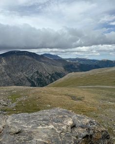 the view from the top of a mountain looking down at some hills and mountains in the distance