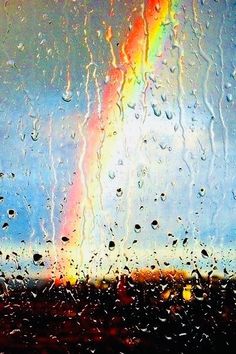 a rainbow is seen through the rain on a window