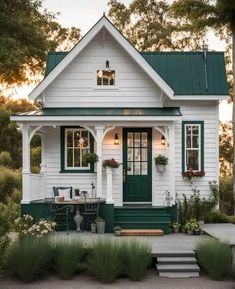 a small white house with green trim on the front door and steps leading up to it