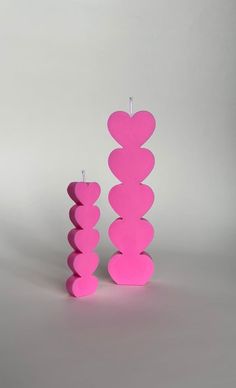 a pink candle sitting on top of a table next to a stack of hearts shaped candles