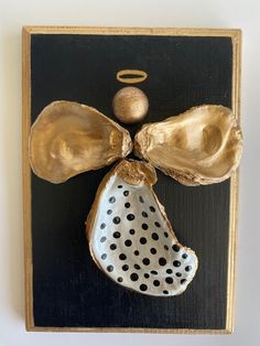 a black and gold plaque with an angel's wing on it, hanging from the wall