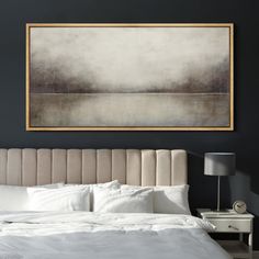 a large painting hangs above a bed with white linens and pillows on the headboard