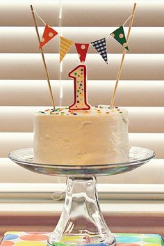 a birthday cake sitting on top of a table next to a window covered in blinds