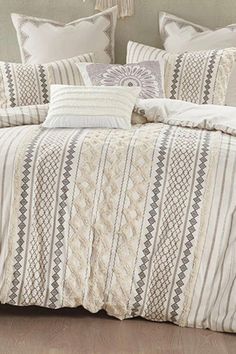 a bed covered in white and grey striped comforter