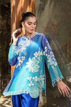 A blue ombre organza shirt is delicately rendered with bold ivory embroidery in a floral and fruit imagery. Featuring a keyhole neckline and scalloped sleeves, the shirt is paired with a royal blue rawsilk shalwar. Model Height is 5'9 and Shirt length is 32" Spring Blue Silk Salwar Kameez, Blue Silk Salwar Kameez For Spring, Designer Floral Embroidered Organza Blouse, Designer Organza Blouse With Floral Embroidery, Georgette Tops With Dupatta For Eid, Eid Georgette Tops With Dupatta, Silk Blouse With Sheer Dupatta, Spring Blue Georgette Kurta, Blue Embroidered Summer Sets