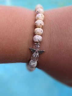 a woman's arm with a bracelet made out of shells and beads on it