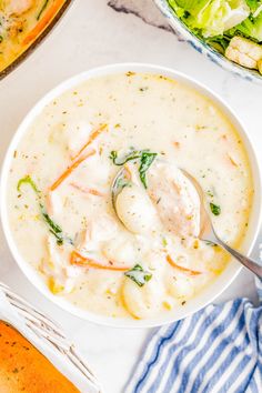 a white bowl filled with soup next to a salad