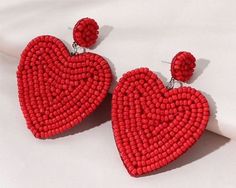 red beaded heart shaped earrings on white background