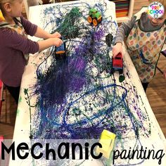 two children at a table with paint and toys