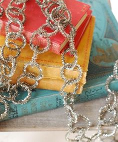 a stack of books sitting on top of a table next to a silver chain necklace