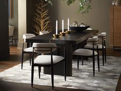 a dining room table with white chairs and candles