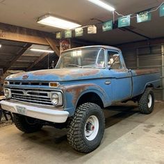 an old blue truck parked in a garage