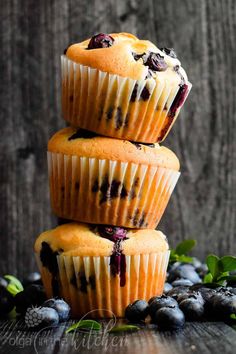 three blueberry muffins stacked on top of each other next to fresh blueberries