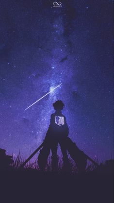 a person standing in the grass under a night sky with a shooting star above them