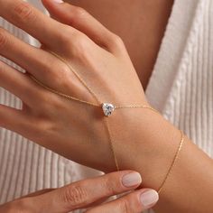 This beautiful hand chain is crafted from sterling silver and features a dainty chain. The centerpiece of the chain showcases a stunning heart-shaped zircon gemstone, exuding a casual yet sophisticated vibe. Show off your romantic side (without being cheesy) with this delicate design. Metal: 925 sterling silver Finish: 18k gold Gemstone: white zirconia Bracelet length: adjustable with 4 cm extender (1.5") Chain: cable link Clasp: spring ring Hypoallergenic, nickel-free Don’t forget, proper care Heart-shaped Chain Jewelry For Weddings, Delicate Heart Cut Clavicle Chain Jewelry, Valentine's Day Crystal Jewelry With Adjustable Chain, Diamond Chain Bracelet Tarnish Resistant As Gift, Valentine's Day Cubic Zirconia Chain Jewelry, Luxury Adjustable Heart-shaped Jewelry, Elegant Chain Bracelet With Adjustable Heart Pendant, Elegant Chain Bracelet With Heart Pendant And Adjustable Chain, Elegant Chain Bracelet With Heart Pendant