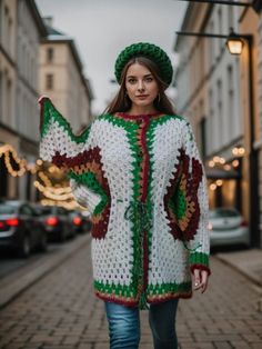 a woman is walking down the street wearing a crocheted sweater and green hat