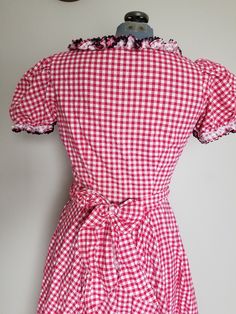 "Super adorable 1950's western style dress. This would be perfect for a dancing date! Or Valentines day! The dress has a fitted bodice with a side metal zipper and an 8 paneled circle skirt with some gathers. The dress also comes with a sash that can be tied around the waist or used as a hair decoration. Sleeves are puffed and there is black ric-rac trim adorning all the ruffles. Condition: Great vintage condition. General, minor signs of wear. I found two very small slight spots of discoloratio Fitted Retro Vintage Dress For Picnic, Fitted Retro Plaid Vintage Dress, Fitted Plaid Retro Vintage Dress, Retro Plaid Fitted Vintage Dress, Fitted Gingham Retro Vintage Dress, Fitted Vintage Gingham Dress In Retro Style, Fitted Gingham Vintage Dress, Retro Fitted Gingham Vintage Dress, Fitted Gingham Plaid Dress With Ruffles