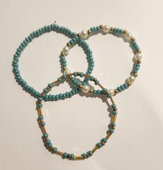 The bracelets are each about 7 inches long and made with stretchy string and glass seed beads. Adjustable Turquoise Stretch Bracelet With Tiny Beads, Turquoise Beaded Bracelets With Gold Beads, Turquoise Beaded Bracelets With Gold Accents, Casual Turquoise Beaded Bracelets With Tiny Beads, Casual Turquoise Spacer Beads, Turquoise Beaded Stretch Bracelet Gift, Blue Heishi Beads Bracelet With Gold Accents, Blue Heishi Beads Bracelet With Gold Beads, Casual Turquoise Beaded Bracelets With Spacer Beads