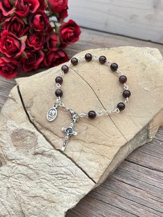 "Beautifully Handmade Rosary bracelet! Beads are 6mm polished Garnet semi-precious stone, Cross is a 7/8\" silver St. Benedict crucifix, and mini medal is a 1/2\" mini medal with amazing details **Mini Medal Choices** 1. Blue Miraculous Mary 2. Miraculous Mary 3. Holy Spirit 4. 5 Way Cross 5. Holy Family / Holy Spirit 6. Guardian Angel / St. Michael Each one of my rosary bracelets starts its life as a spool of wire and a handful of beads. It is carefully assembled one link at a time so no two ar Silver Rosary Bracelet With Gemstone Beads, Silver Rosary Bracelet With Gemstone Beads As Gift, Gift Rosary Bracelet With Polished Beads, Silver Rosary Bracelet With Natural Stones As Gift, Gift Round Rosary Bracelet With Polished Beads, Gift-ready Round Rosary Bracelet With Polished Beads, Garnet Rosary, Catholic Rosary Bracelet, Handmade Rosary