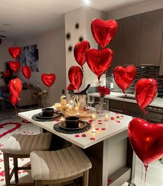 red balloons are floating in the air over a table with candles and plates on it