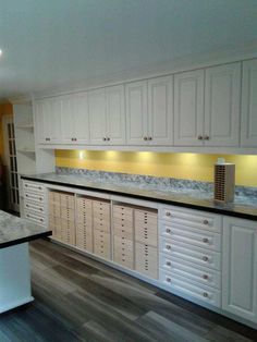 an empty kitchen with white cabinets and granite counter tops, along with wooden flooring