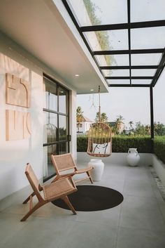 two chairs sitting on top of a cement floor next to a white wall and windows