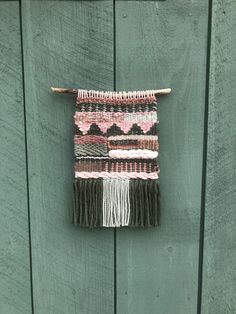 a wall hanging on the side of a green wooden door with fringes and tassels