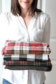 a woman is holding several blankets in her hands and she has one folded over the other