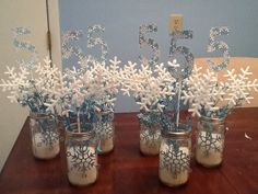 four mason jars with snowflakes in them on a table