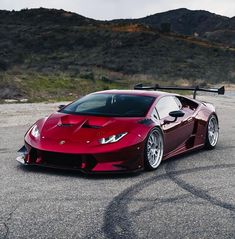 a red sports car parked on top of a parking lot next to a mountain range