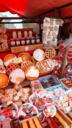 a woman standing in front of a table filled with different types of foods and pastries