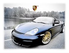 a black sports car parked in front of a lake with the porsche logo above it