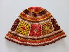 a crocheted hat is displayed on a white surface with an orange, red, yellow and green design