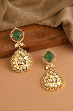 Indulge in sophistication with these Kundan earrings, featuring a striking emerald stone surrounded by sparkling diamonds, exuding timeless elegance and charm. Finish: 22KT Gold Plating Material: Brass, Kundan, Carved Emerald Stone Color: Gold, Green Size: One Size Closure Type: Push Back Box Contains: 1 Pair of Earrings Emerald Earrings Indian, Carved Emerald, Hand Jewelry Rings, Chain Braid, Artificial Jewelry, Kundan Earrings, Jewelry Indian, Emerald Earrings, Emerald Stone