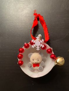 a small christmas ornament with a teddy bear in it on a black table