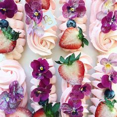 cupcakes decorated with pink frosting and fresh strawberries are arranged in the shape of flowers