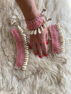 a woman's hand with pink and white beaded bracelets on top of a rug